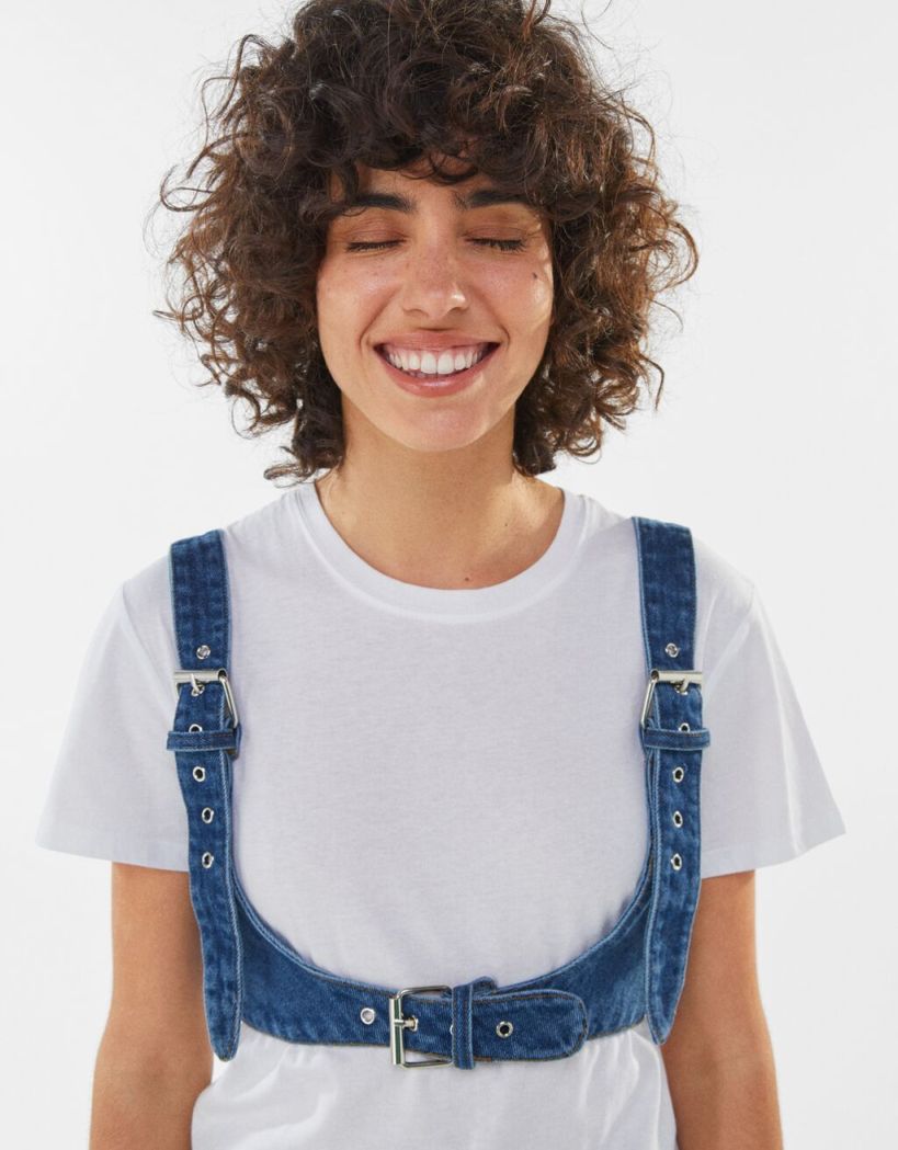 Denim ζώνη με τιράντες που κλείνει κάτω από το στήθος, 7.99€ από 15.99€ , Bershka.