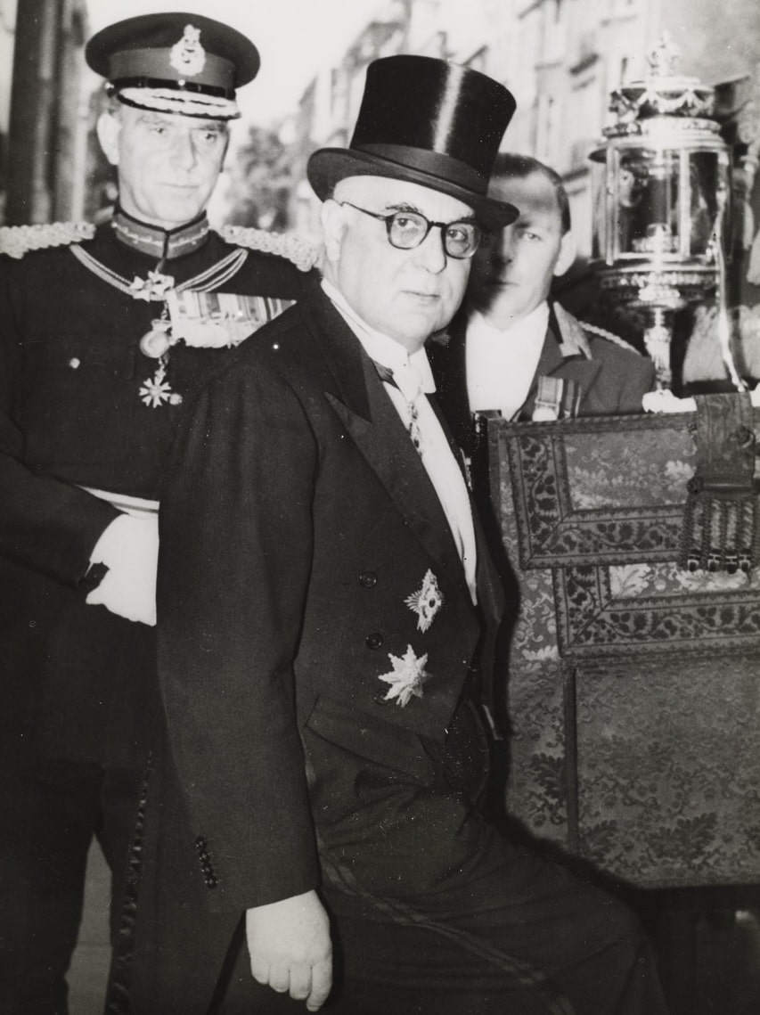 Λονδίνο, 6 Ιουνίου 1957. Ο Γιώργος Σεφέρης μεταβαίνει από την πρεσβευτική κατοικία στο παλάτι του Μπάκινχαμ με την παραδοσιακή άμαξα, όπου θα επιδώσει τα διαπιστευτήρια του στην Βασίλισσα Ελισάβετ. Η φωτογραφία αυτή διανεμήθηκε από το Γαλλικό Πρακτορείο Ειδήσεων την ημέρα της αναγγελίας του Νόμπελ Λογοτεχνίας στον Σεφέρη.